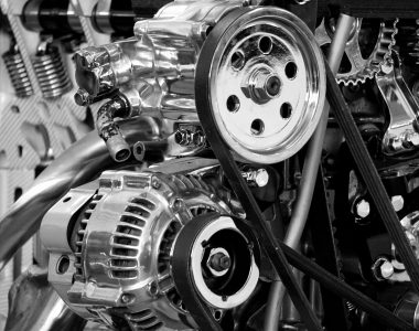 Close-up of a shiny car engine showing polished metal parts and gears in black and white.