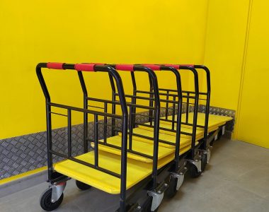 Multiple industrial dollies lined up in a vibrant yellow room.